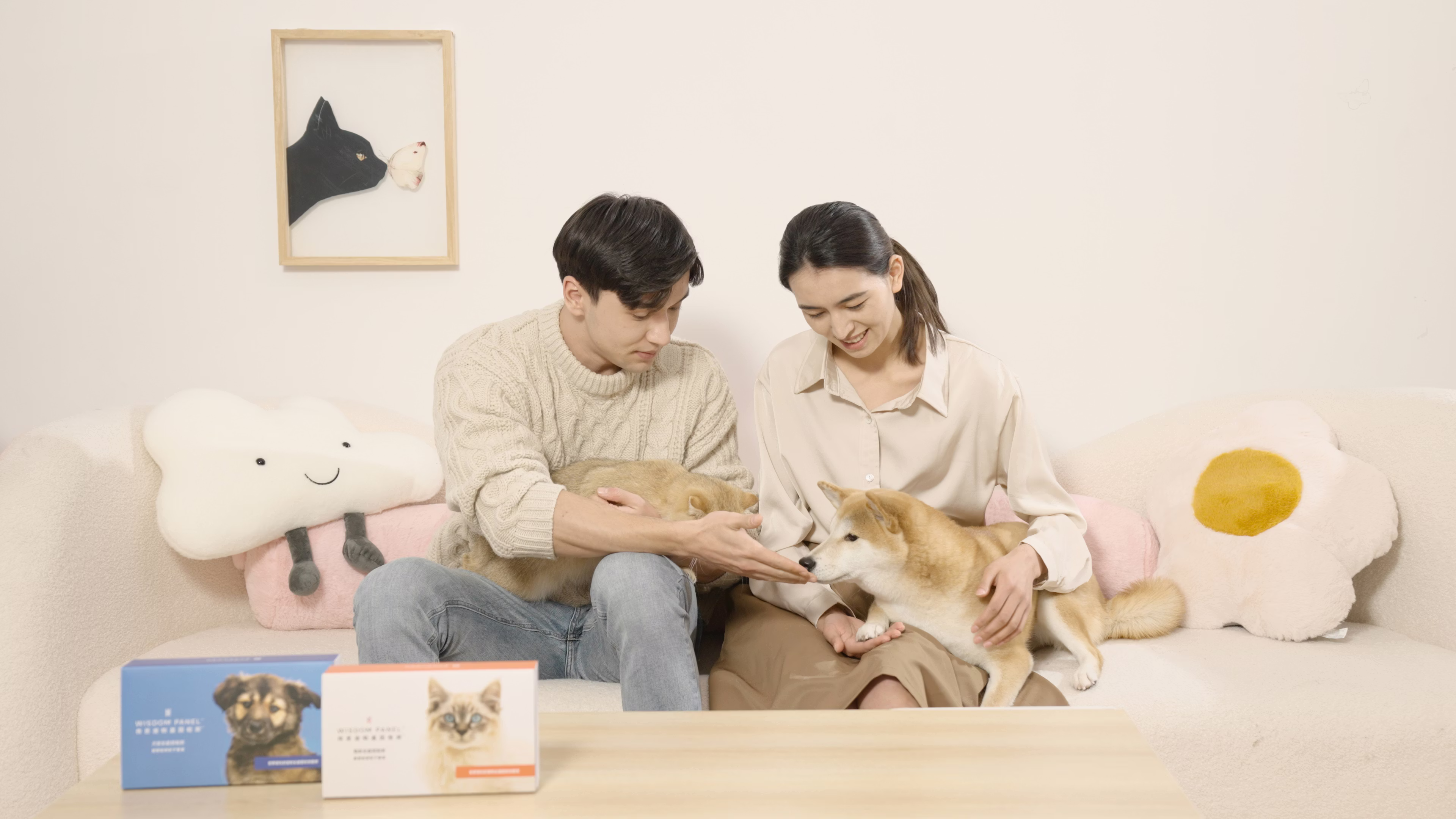 Pet parents with their dog and cat on their laps and two Wisdom Panel DNA kits on the table.